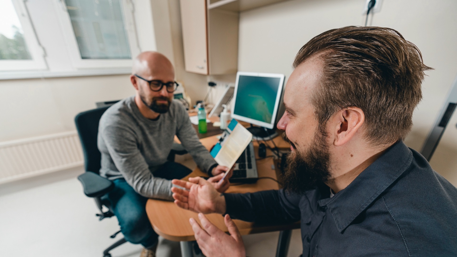 Henkilö näyttää opaskirjaa toiselle henkilölle. Kuva Liikkuva aikuinen, Jussi Judin.