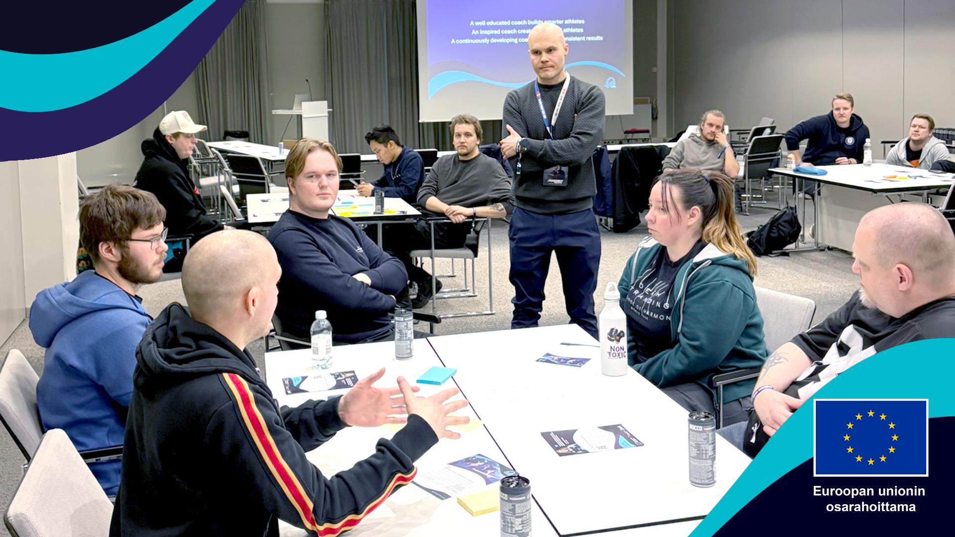 eVAVE-hankkeen työpajaosallistujia pöytien ääressä vaaleasävyisessä neuvotteluhuoneessa. Tilannetta seuraa seisaaltaan Otto Takala.