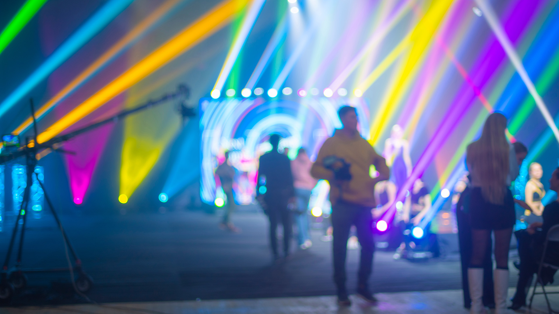 Isossa tapahtumatilassa värivalojen edustalla näkyviä nuoria ihmisiä.