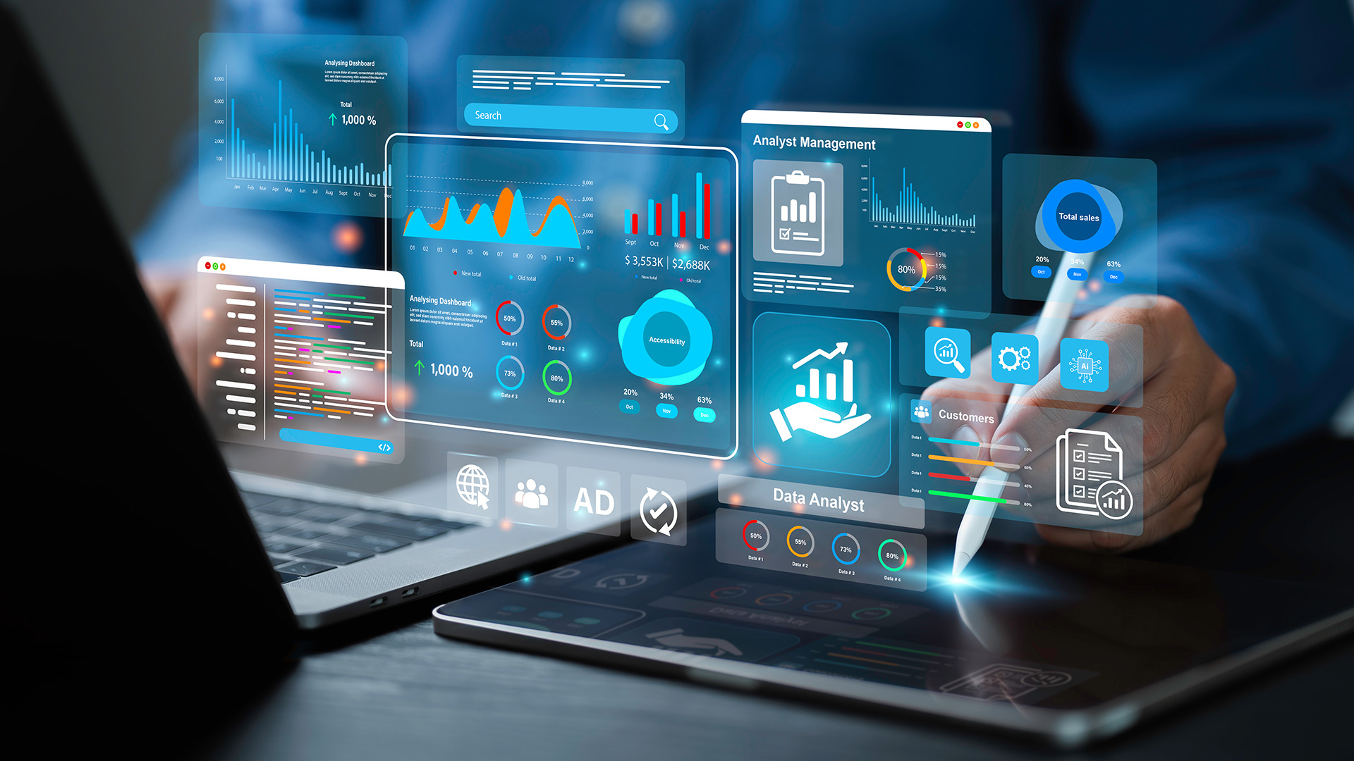 Henkilö käyttää tietokonetta ja tablettia, ja hänen edessään näkyy hologrammina visualisoitua dataa.