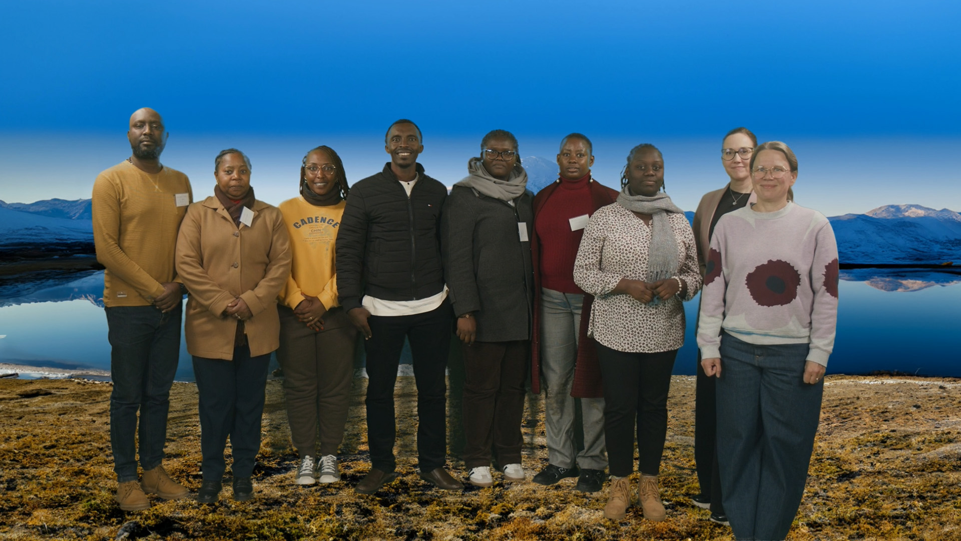 HEP-TED project training programme participants in a group photo at Jamk's studio with a mountain and lake scenery as their background.