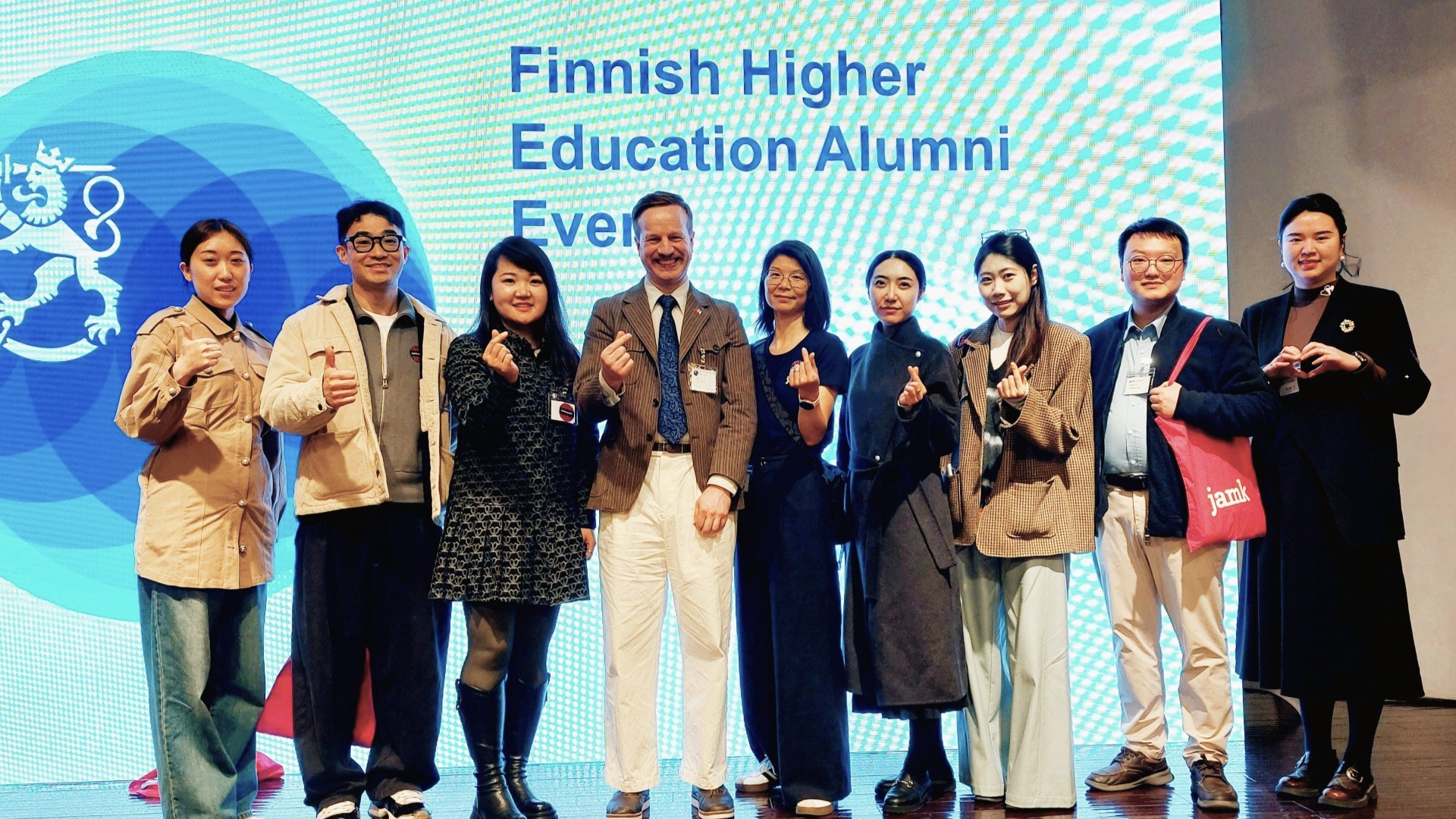 Jamkin kiinalaiset alumnit, suurlähetystön edustaja ja Jamkin henkilökunnan jäsen seisovat rivissä hymyillen