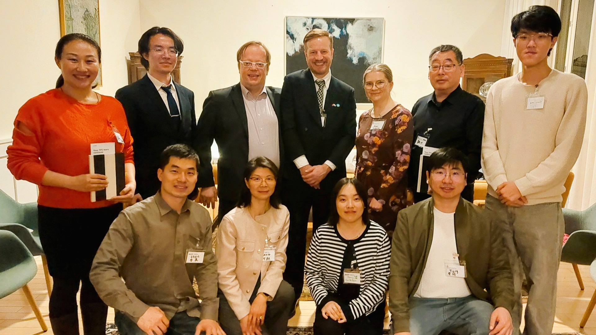 Jyväskylässä opiskelleet kiinalaiset alumnit, suurlähetystön ja korkeakoulujen edustajat katsoat hymyillen kameraan