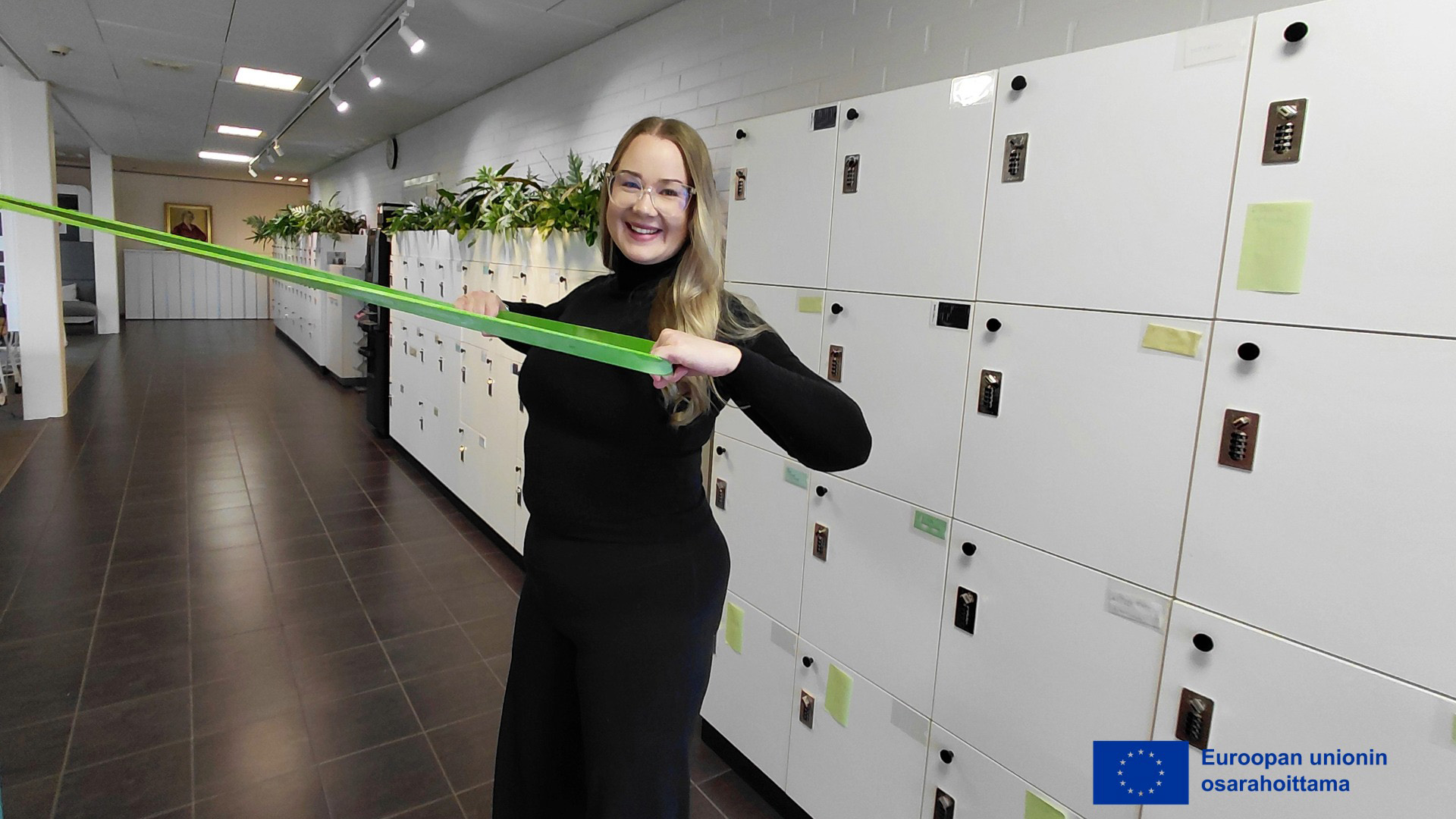 Henkilö venyttelee kuminauohoilla toimistossa.