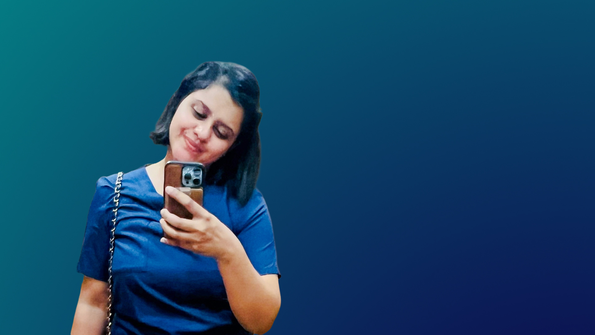Thisari smiles as she looks at the phone in her hand. She is wearing a blue shirt.