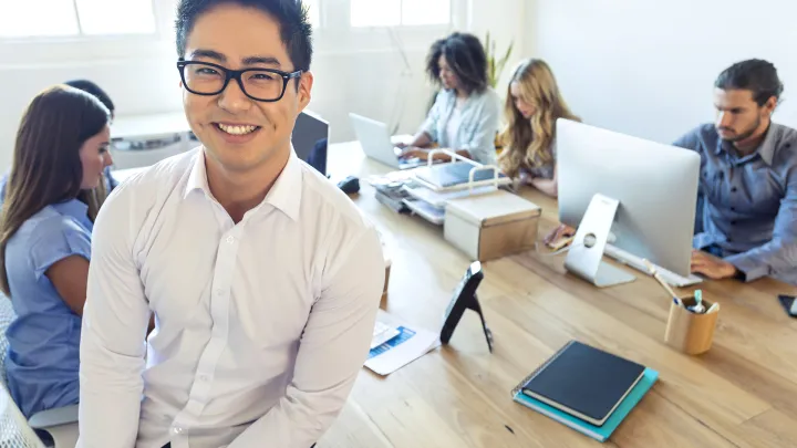 Young man and five other persons working in the office 