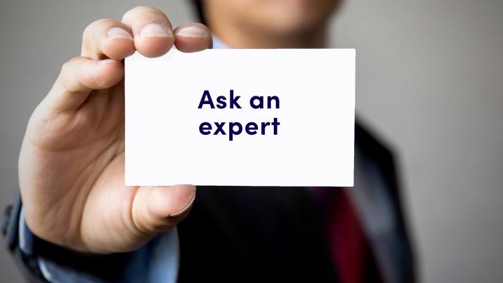 Businessman presenting 'Ask An Expert' word on white card