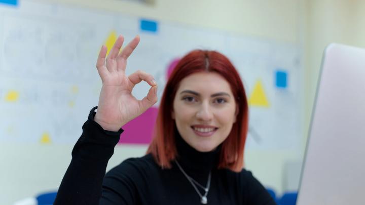 Opiskelija näyttää kädellä OK-merkkiä