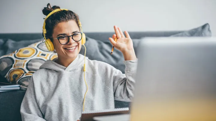 A happy student on a laptop with head phones