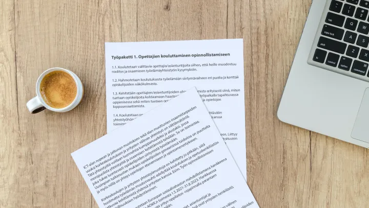 Papereita tietokoneen vieressä pöydällä