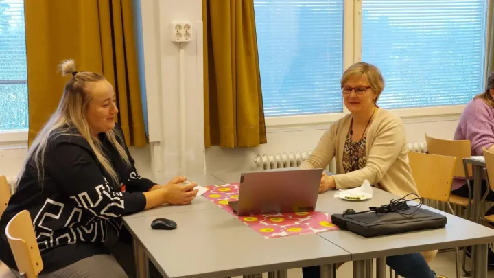 kaksi naista keskustelemassa koneen äärellä
