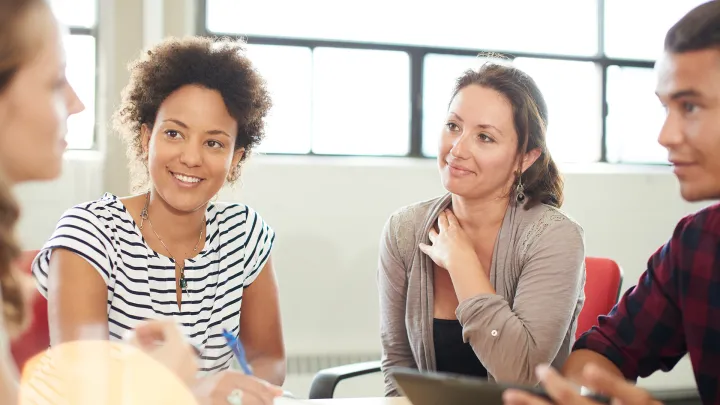 Neljä nuorta henkilöä keskustelee ja katsoo toisiaan pöydän äärellä
