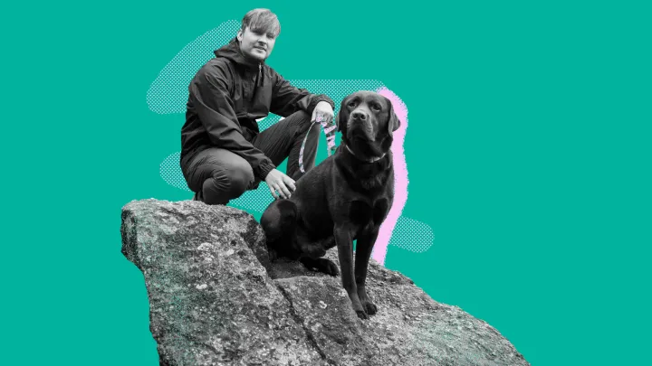 Henkilö istuu koiran kanssa kivellä. Tausta on tummanvihreä.