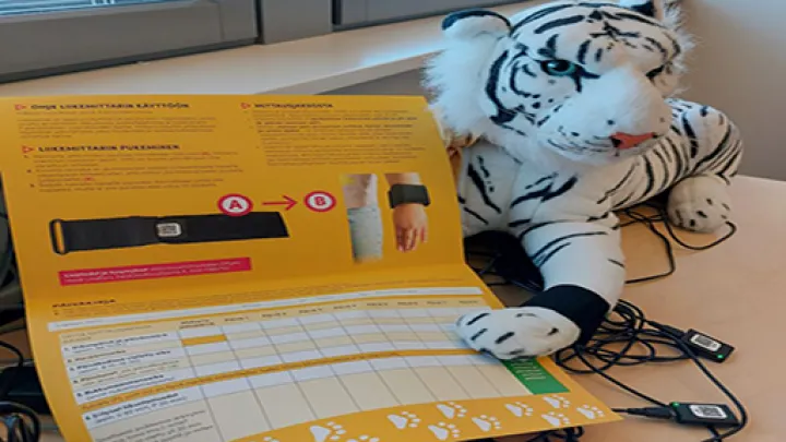 Lelu-tiikerillä liikemittari ranteessa, liikemittareita ja päiväkirja.