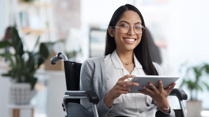a woman holding a tablet device while sitting in a wheelchair