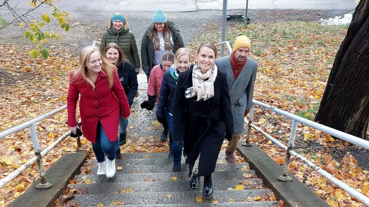 Henkilöitä nousee rappusia syksyisessä kaupungissa.