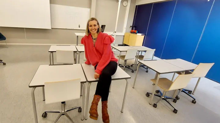 Heidi Syväoja istuu luokkahuoneessa pulpetilla.