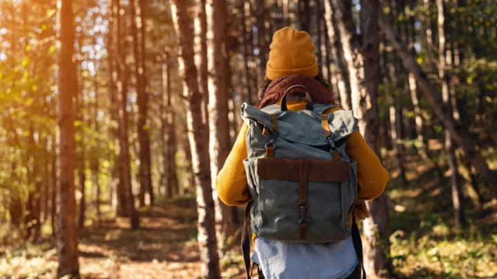 Henkilö kävelee reppu selässä metsässä.