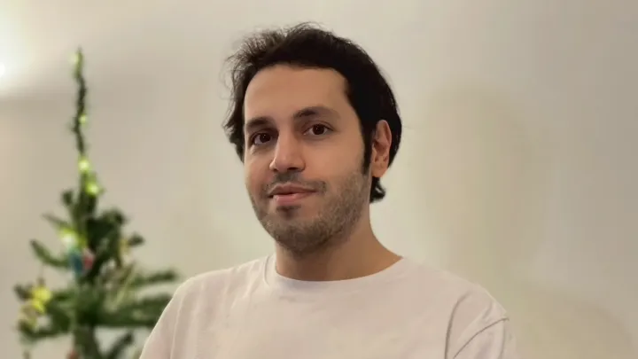 A person in a white shirt smiling in the middle of the picture.