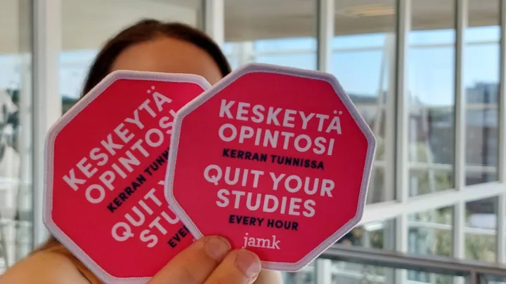 Henkilö pitää kädessä haalarimerkkejä.