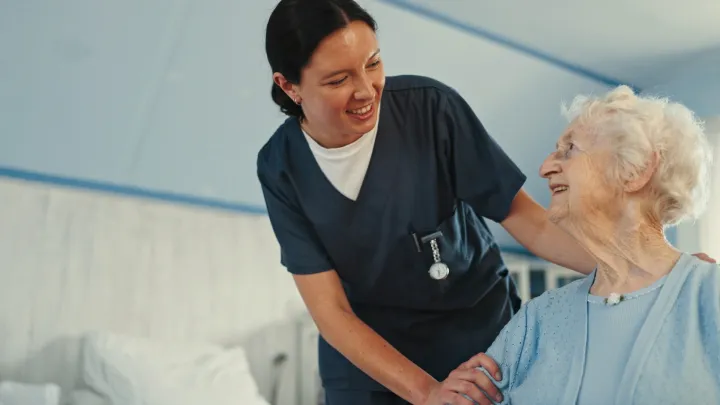 Hoitaja keskustelemassa istuvan vanhan naisen kanssa.