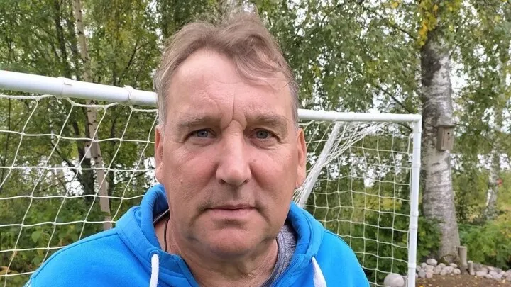 Henkilökuva miehestä sinisessä hupparissa. Taustalla jalkapallomaali.